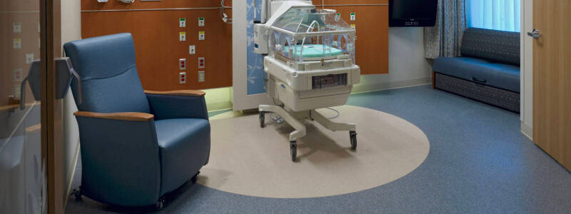 Hospital NICU suite with circular cream flooring surrounded by a blue perimeter. This image is meant to demonstrate expertise in healthcare flooring.